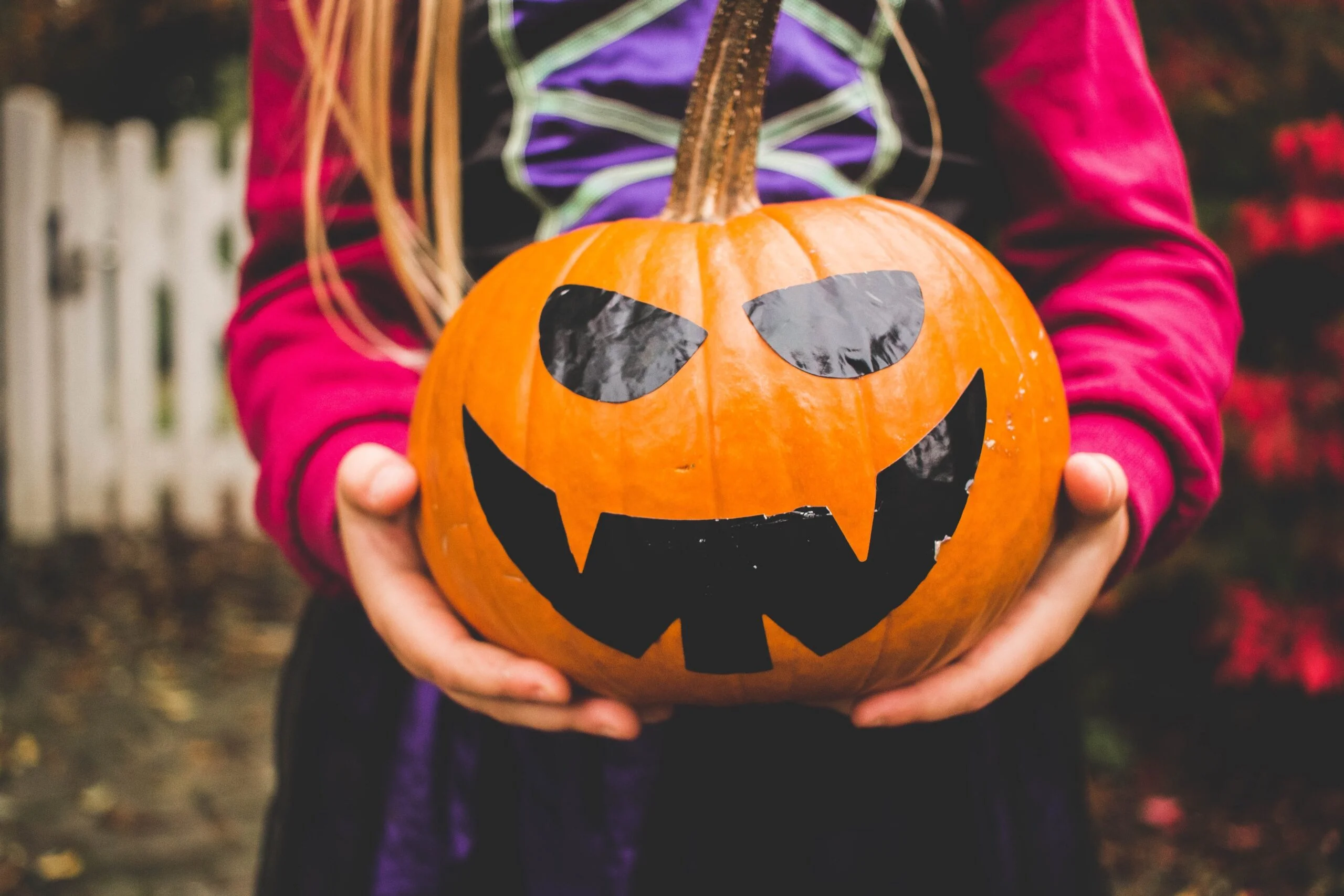 Kind hält dekorierten Halloween Kürbis vor Körper