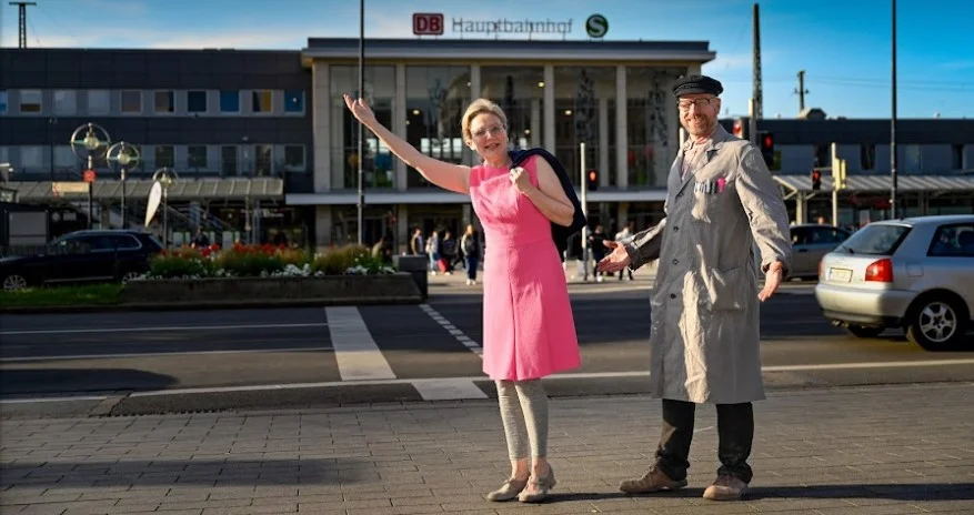 Hetti (links) und Jupp (rechts) begrüßen Spieler*innen vor dem Dortmunder Hauptbahnhof
